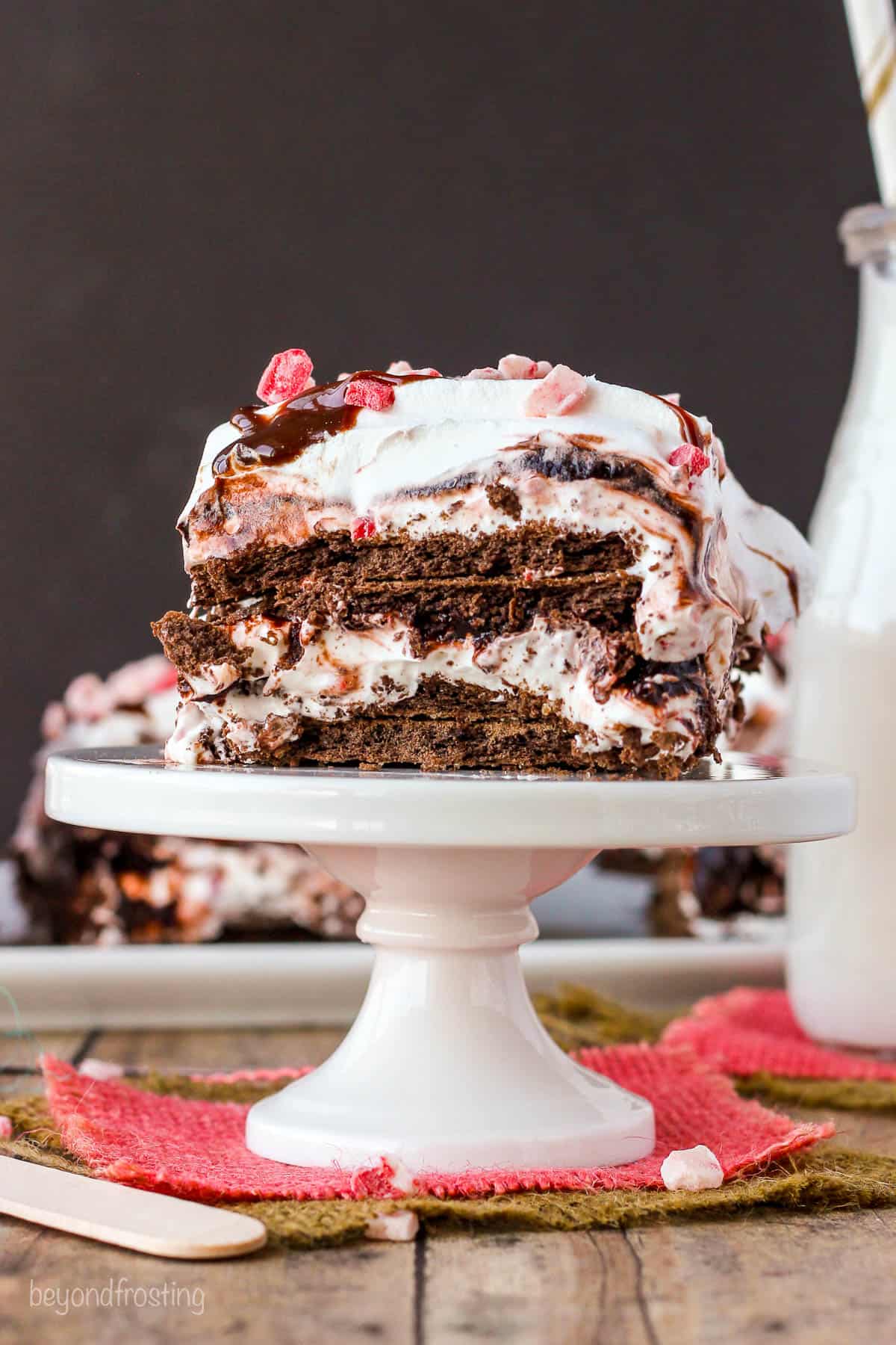 white tray holding a slice of no-bake chocolate peppermint lasagna with a jug of milk in the background