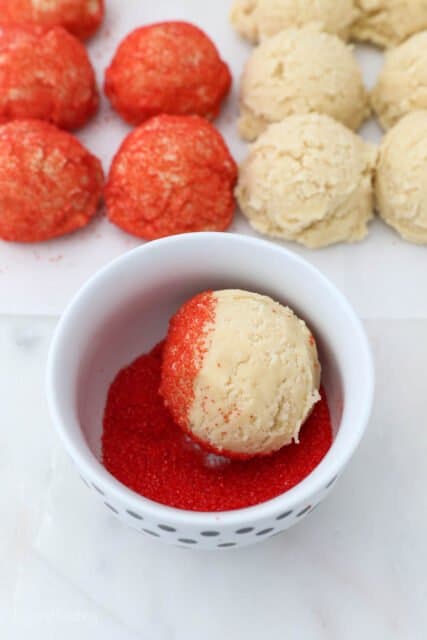 sugar cookie dough being rolled in red sprinkles