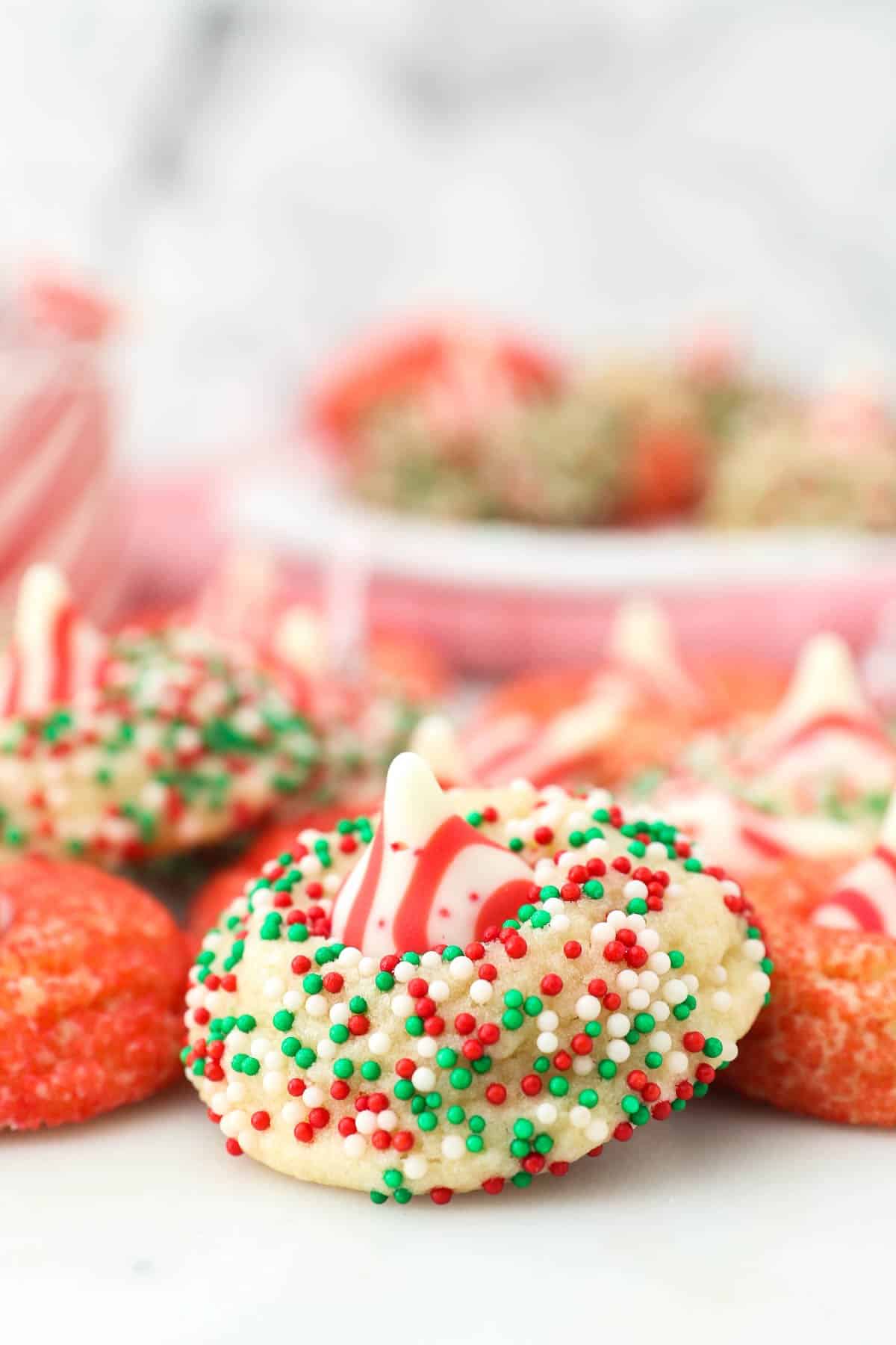 closeup of sugar cookie with red, green, and white sprinkles with other festive cookies in the background
