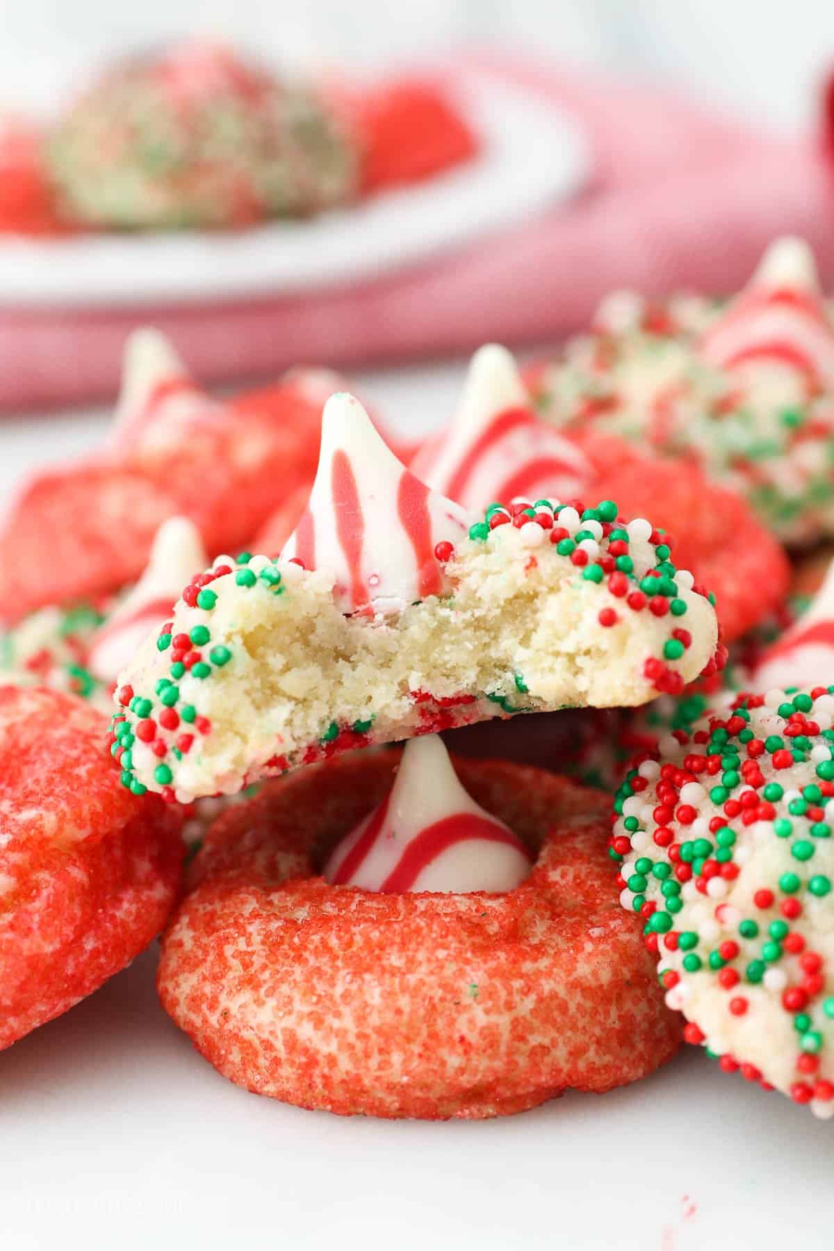 christmas cookies piled on a plate, one with a bite taken out