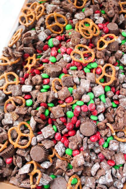 a sheet pan with Reindeer chow snack mix with pretzels, M&Ms, Reese's peanut butter cups and puppy chow