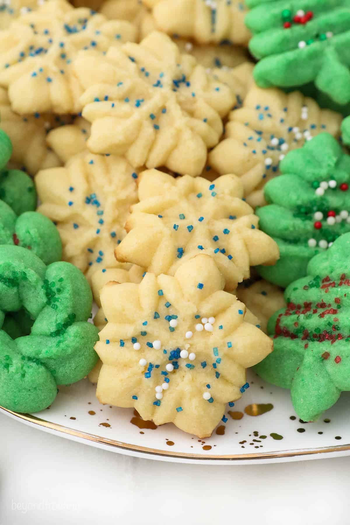 Green and off-white spritz cookies piled high onto a large serving plate