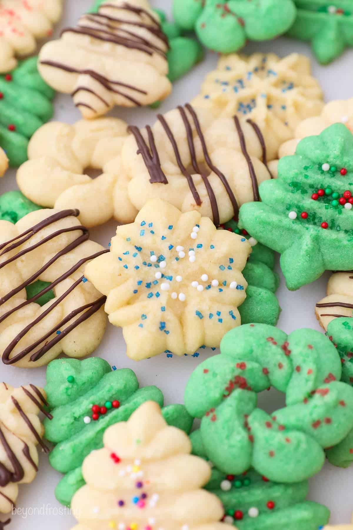 A bunch of green and white spritz cookies piled onto a white countertop