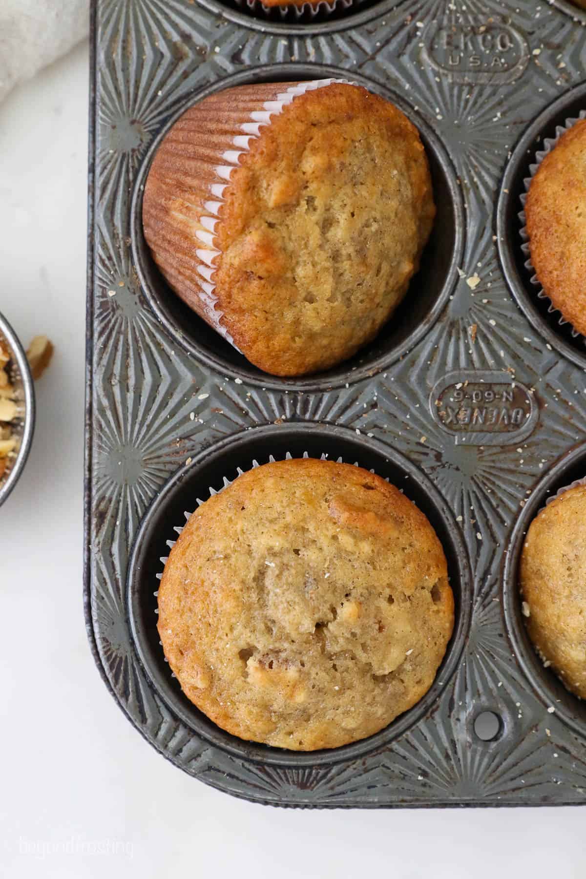 Two banana nut muffins inside of a metal cupcake pan
