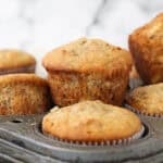 A close-up shot of banana walnut muffins piled onto a six-count muffin tin