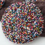 A sprinkle-covered chocolate sugar cookie propped up against more cookies