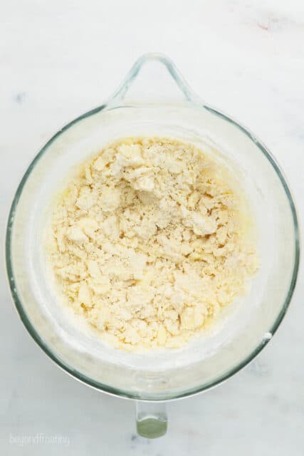 A glass mixing bowl with crumbled butter, sugar and flour