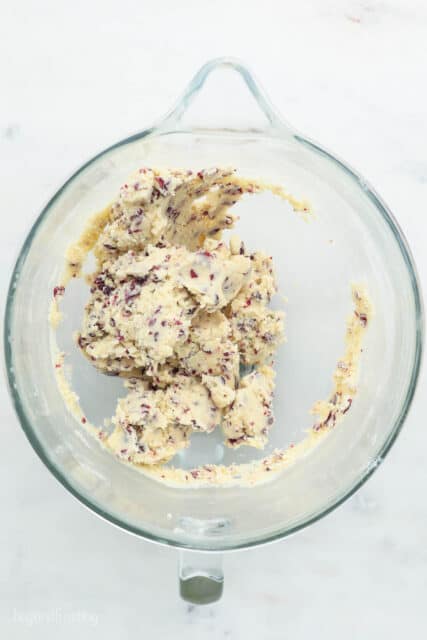 A glass mixing bowl of a finished cranberry almond shortbread dough