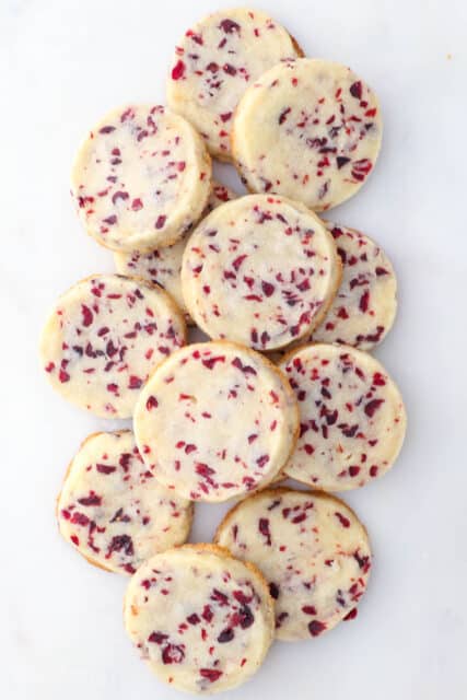 Overhead view of stacked cranberry shortbread cookies on a marble surface