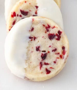 A close up of a white chocolate dipped cranberry shortbread cookie