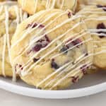 A close up of cranberry orange cookies drizzled with chocolate on a white plate