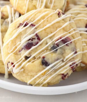 A close up of cranberry orange cookies drizzled with chocolate on a white plate