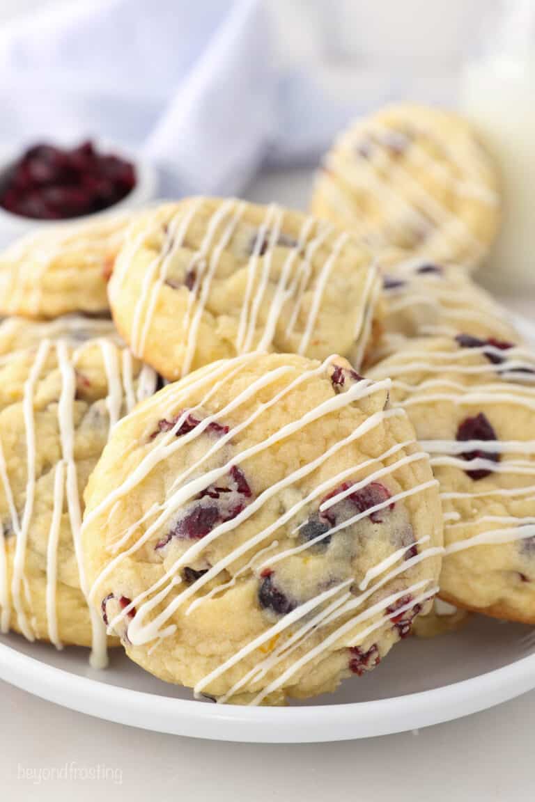 A white plate with cranberry orange cookies drizzled with chocolate