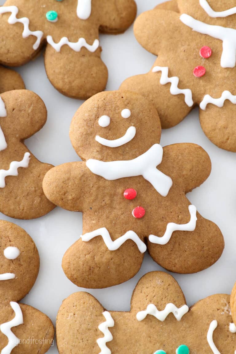 A gingerbread man cookie decorated with a face and clothes with more decorated cookies beside it