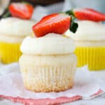 closeup of a frosted champagne cupcake topped with strawberry
