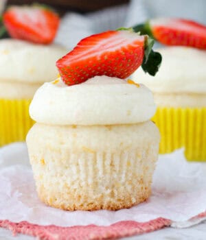 closeup of a frosted champagne cupcake topped with strawberry
