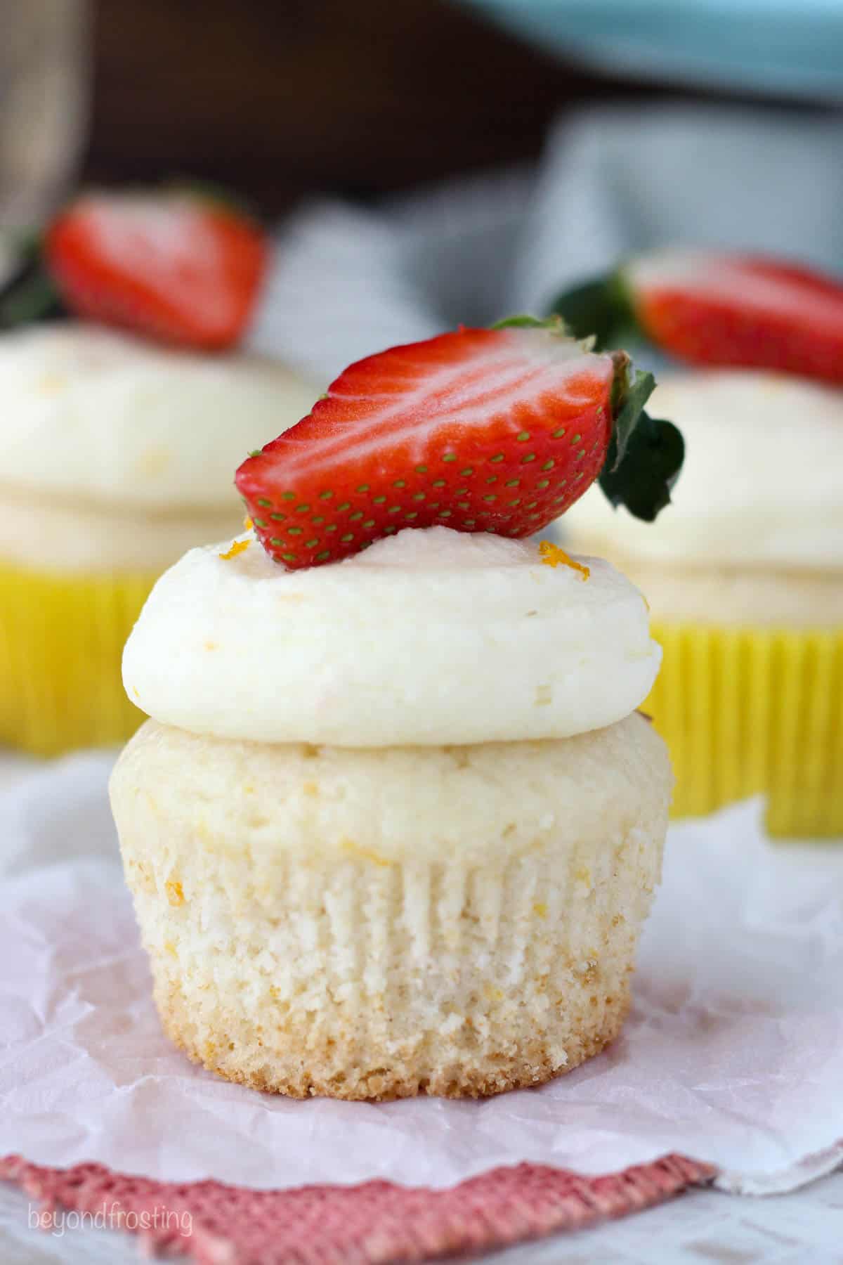 side view of a champagne cupcake topped with half strawberry