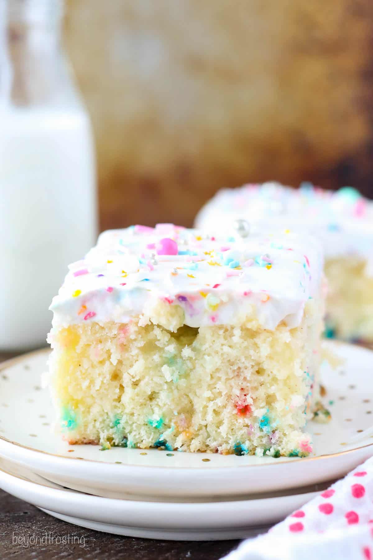 Side view of a slice of funfetti cake on two stacked white plates.