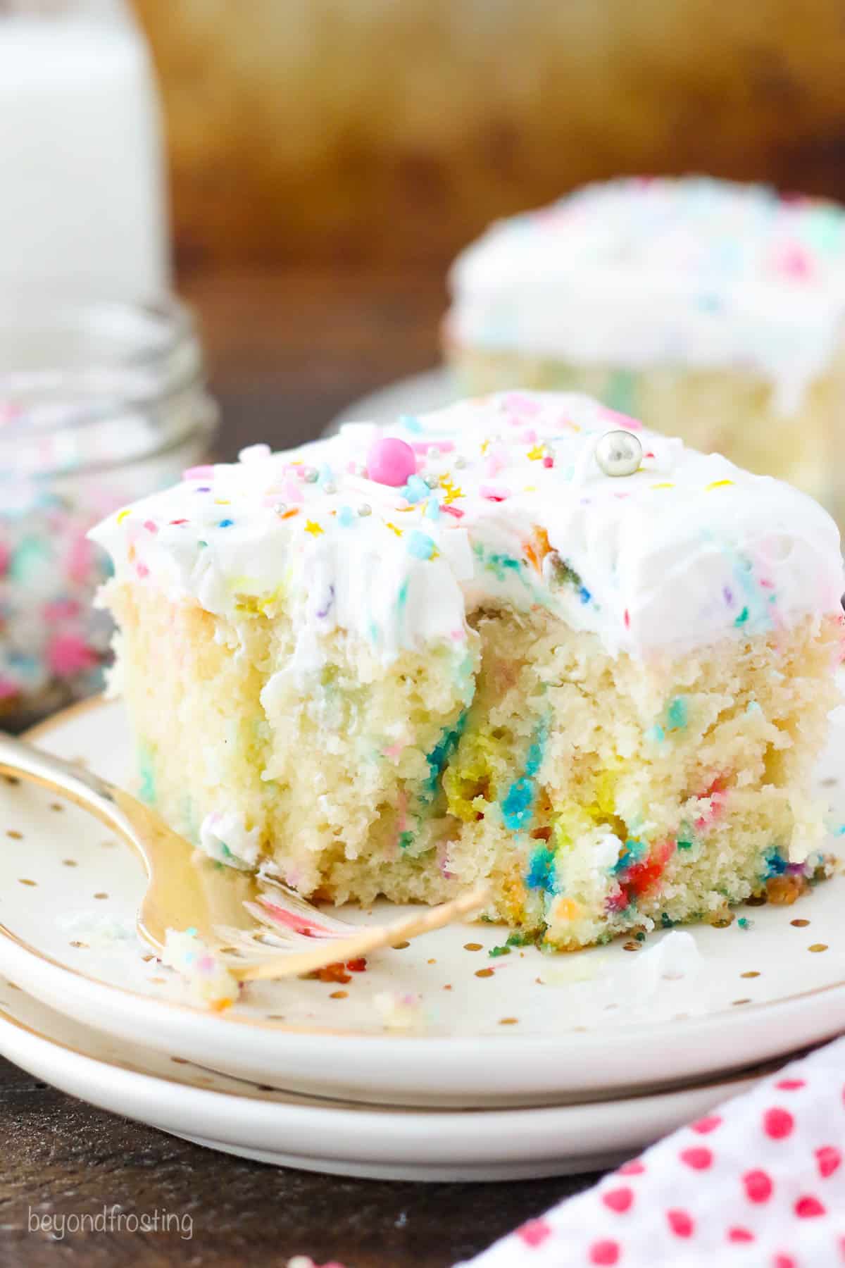 a slice of funfetti cake on a plate with a bite taken out