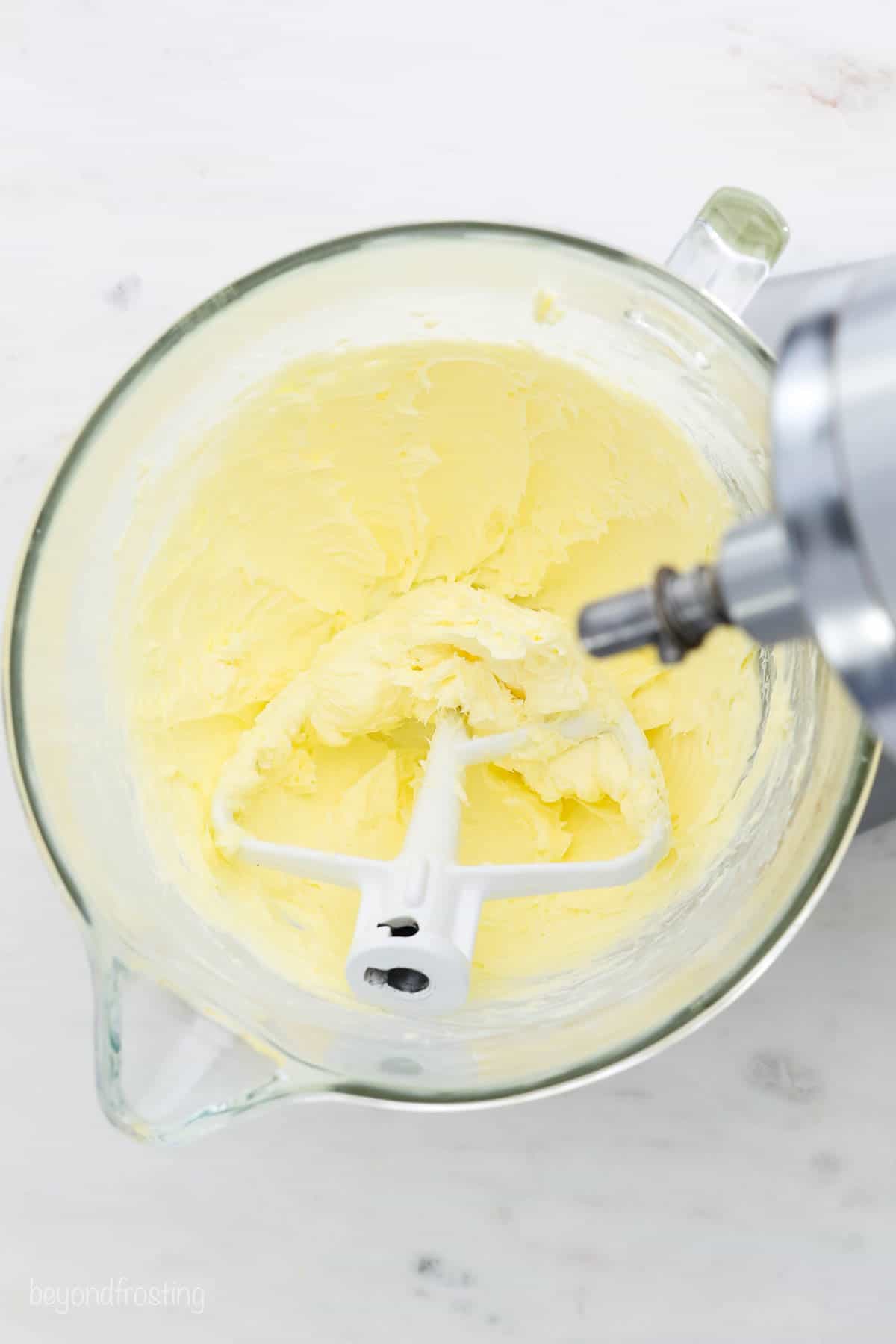 This is the best chocolate frosting recipe! It’s a homemade buttercream made with cocoa powder, and it's perfect for frosting and decorating. A glass mixing bowl with whipped butter