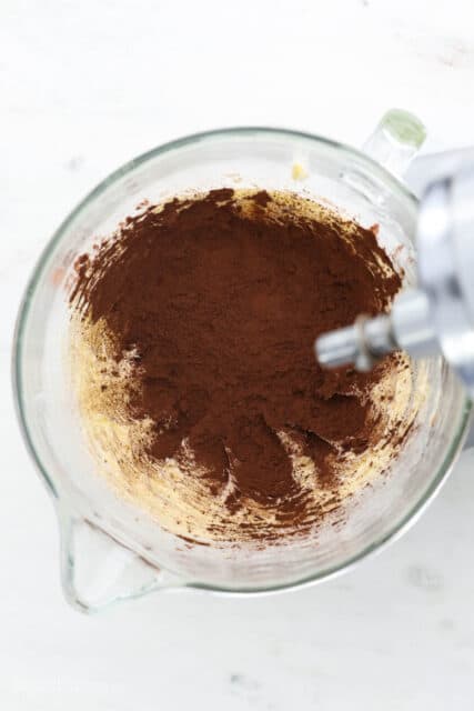 A glass mixing bowl with butter and cocoa powder