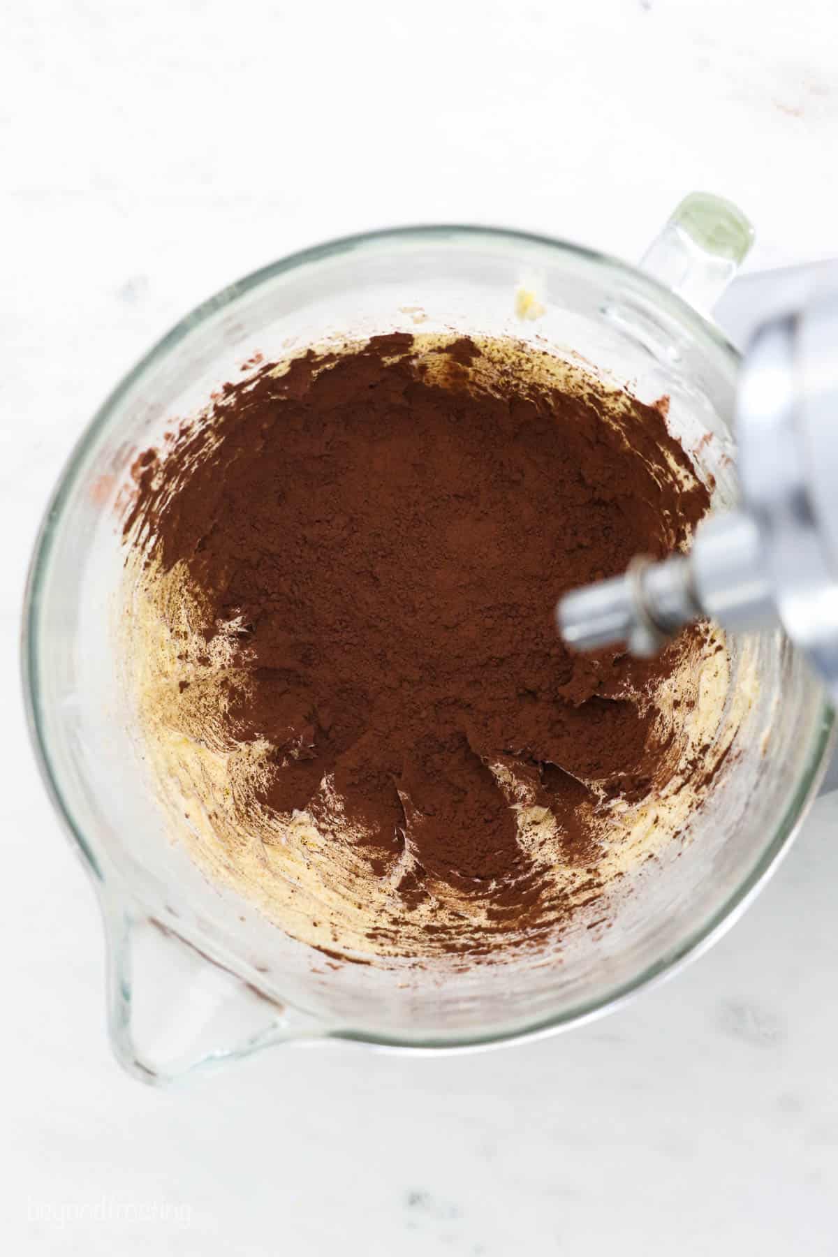 This is the best chocolate frosting recipe! It’s a homemade buttercream made with cocoa powder, and it's perfect for frosting and decorating. A glass mixing bowl with butter and cocoa powder
