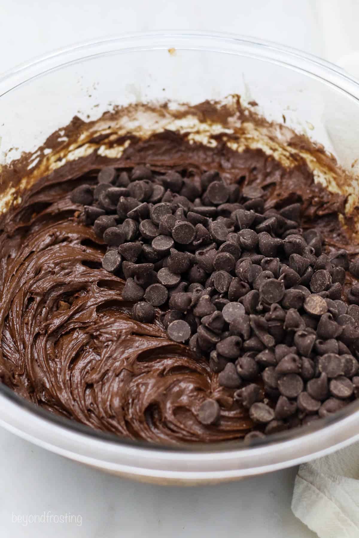 A glass mixing bowl with brownie batter and chocolate chips