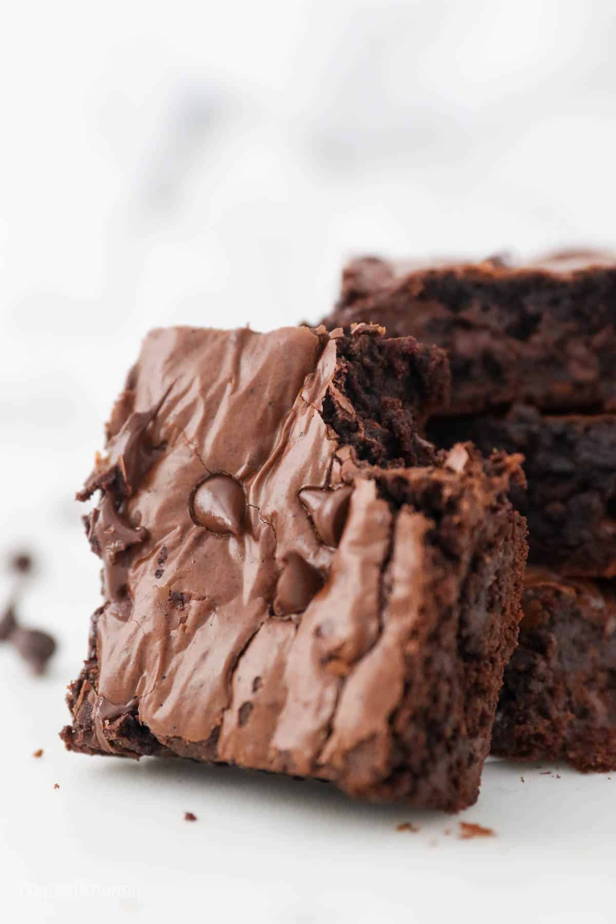 A brownie with a bite taken out of it, leaned up against a stack of more brownies