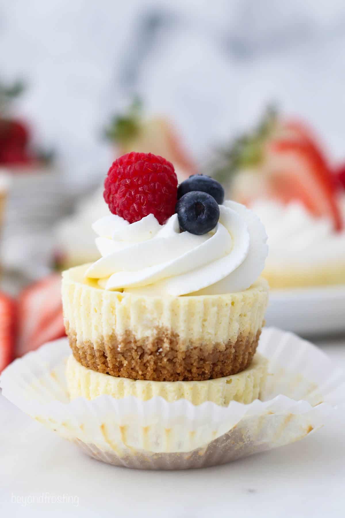 two stacked, unwrapped mini cheesecakes with fruit on top