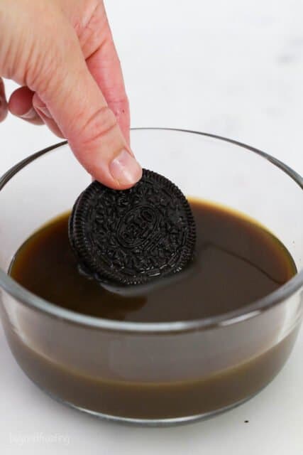 an Oreo being dunked into a bowl of coffee