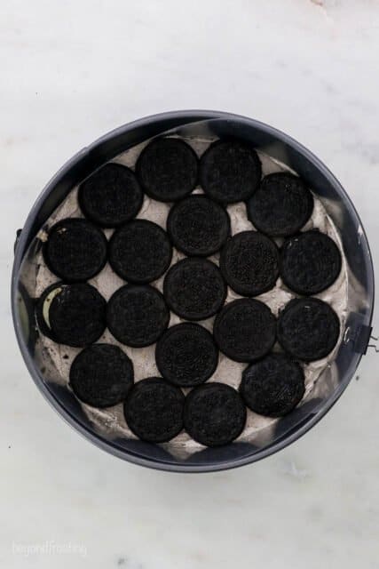 A view down into a round baking pan showing Oreos laid out in a pattern