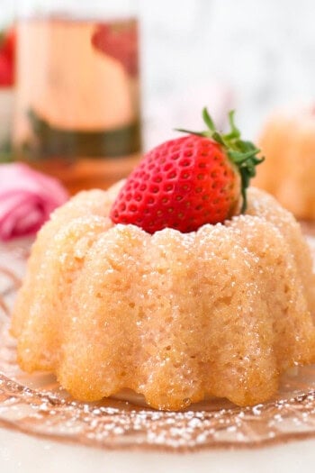 A pink glass glass with a mini bundt cake topped with a strawberry