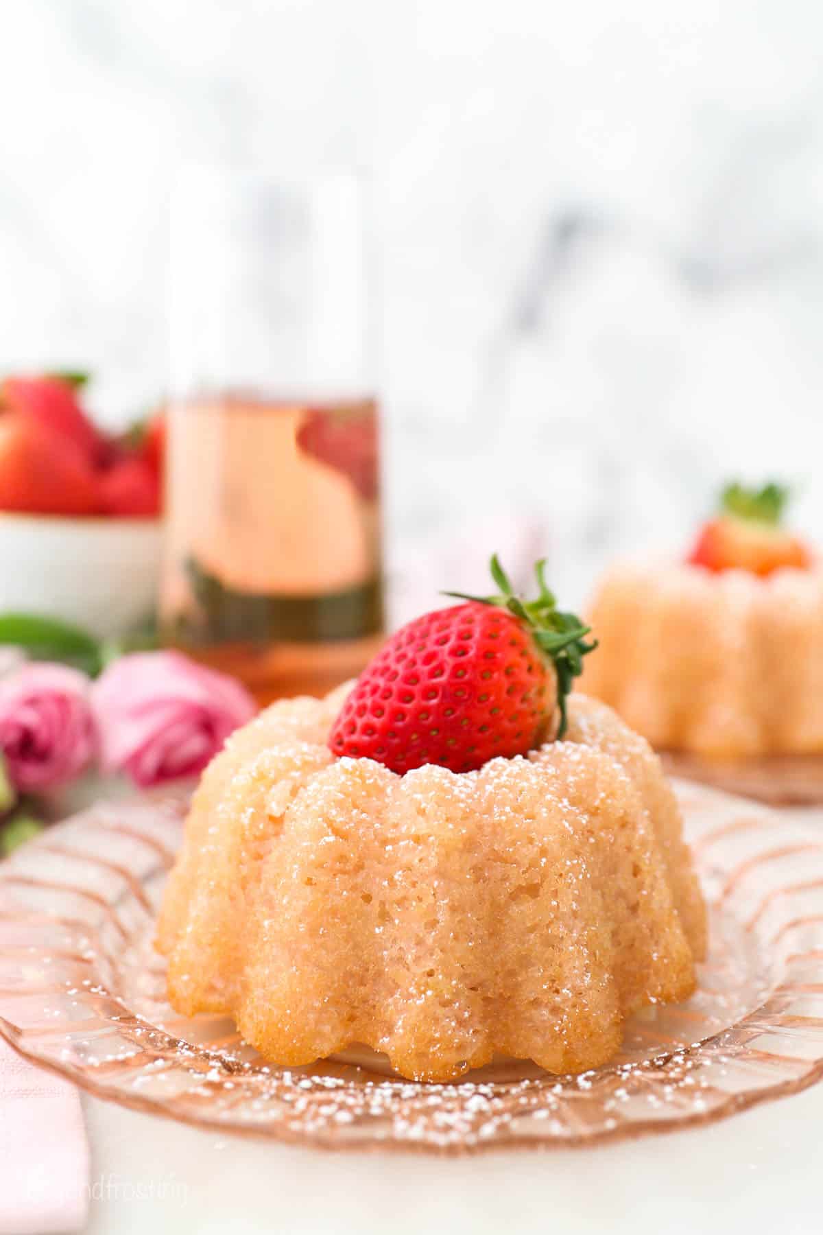 A pink glass glass with a mini bundt cake topped with a strawberry