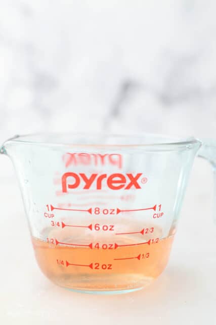 Pyrex glass measuring cup filled with 1/2 cup of sparkling rosé