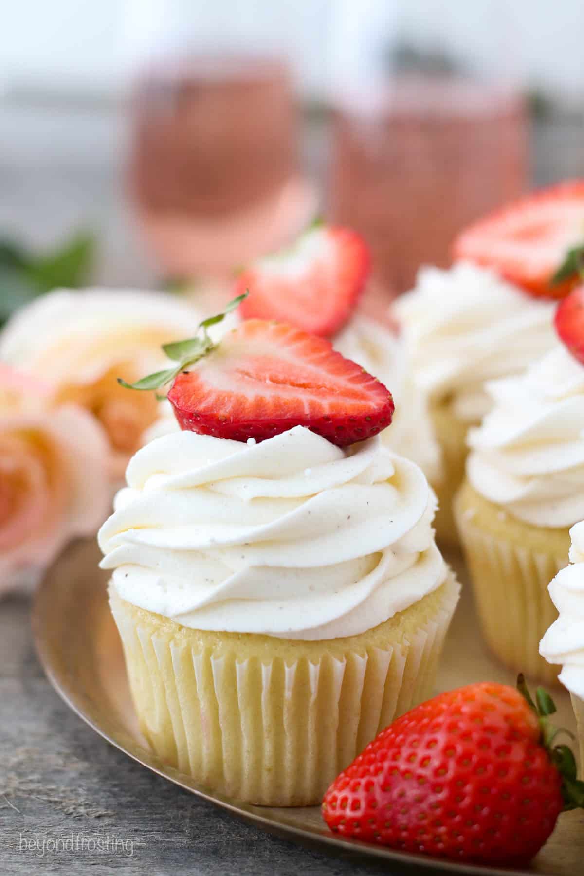 frosted rosé cupcakes on a gold tray with strawberries