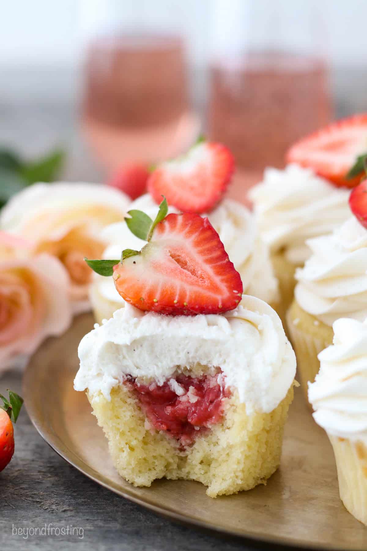 rosé cupcake with a bite out topped with half a strawberry