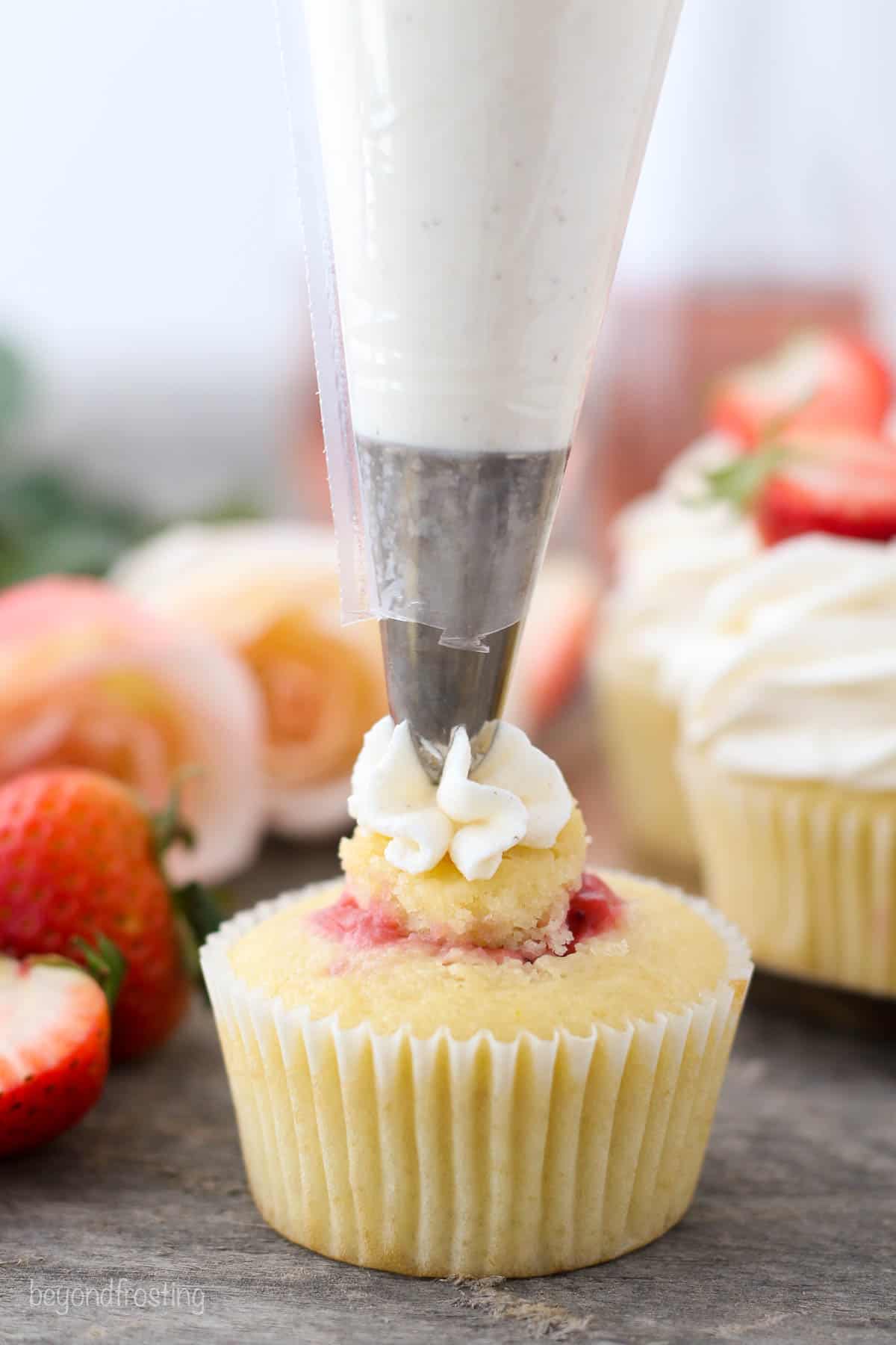 cupcake being topped with buttercream frosting with a piping bag