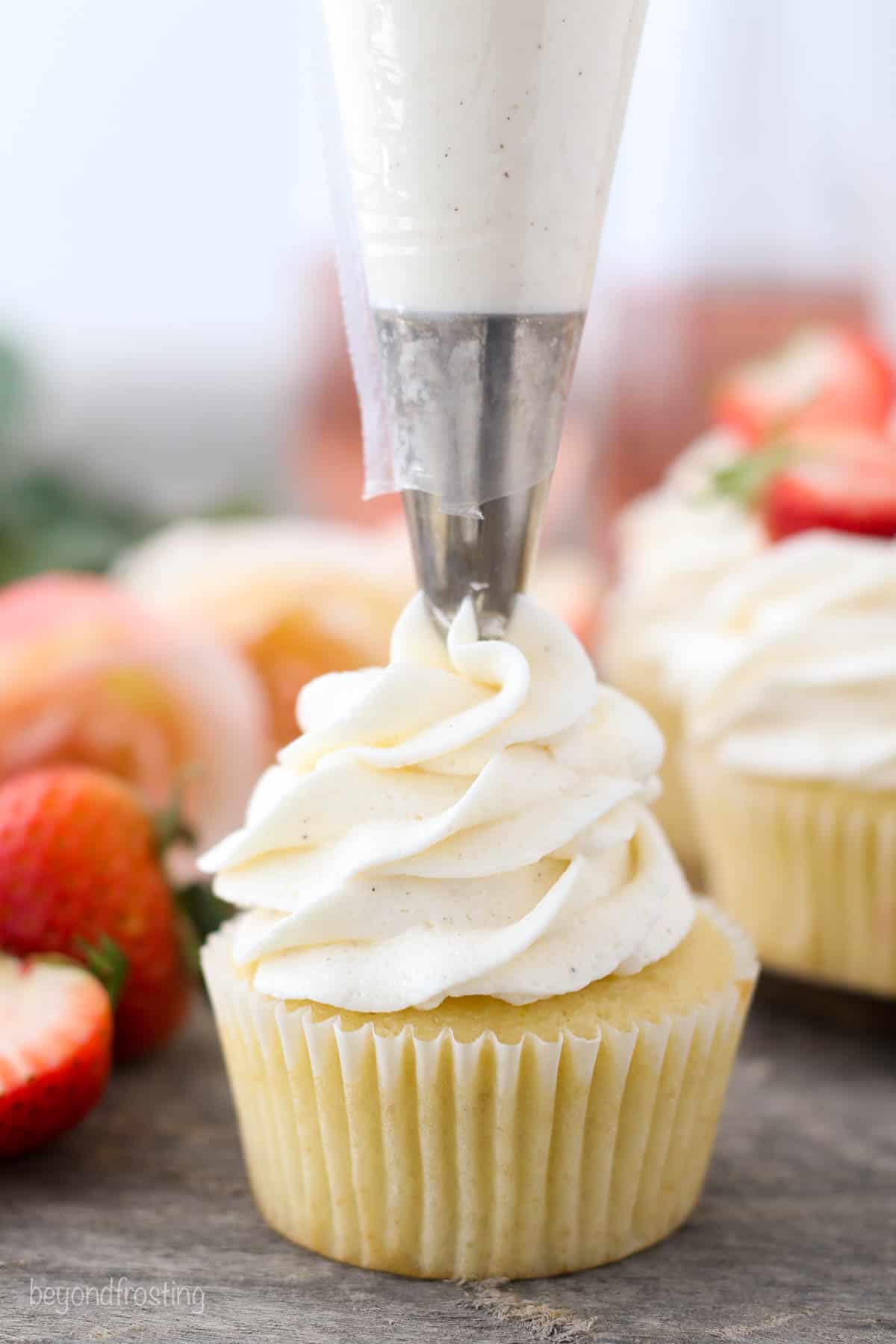 buttercream frosting being piped onto a strawberry rosé cupcake