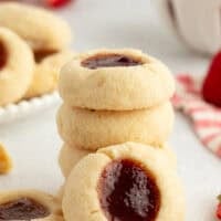 A thumbprint cookie propped up against a stack of cookies.