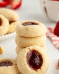 A thumbprint cookie propped up against a stack of cookies.