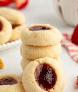A thumbprint cookie propped up against a stack of cookies.