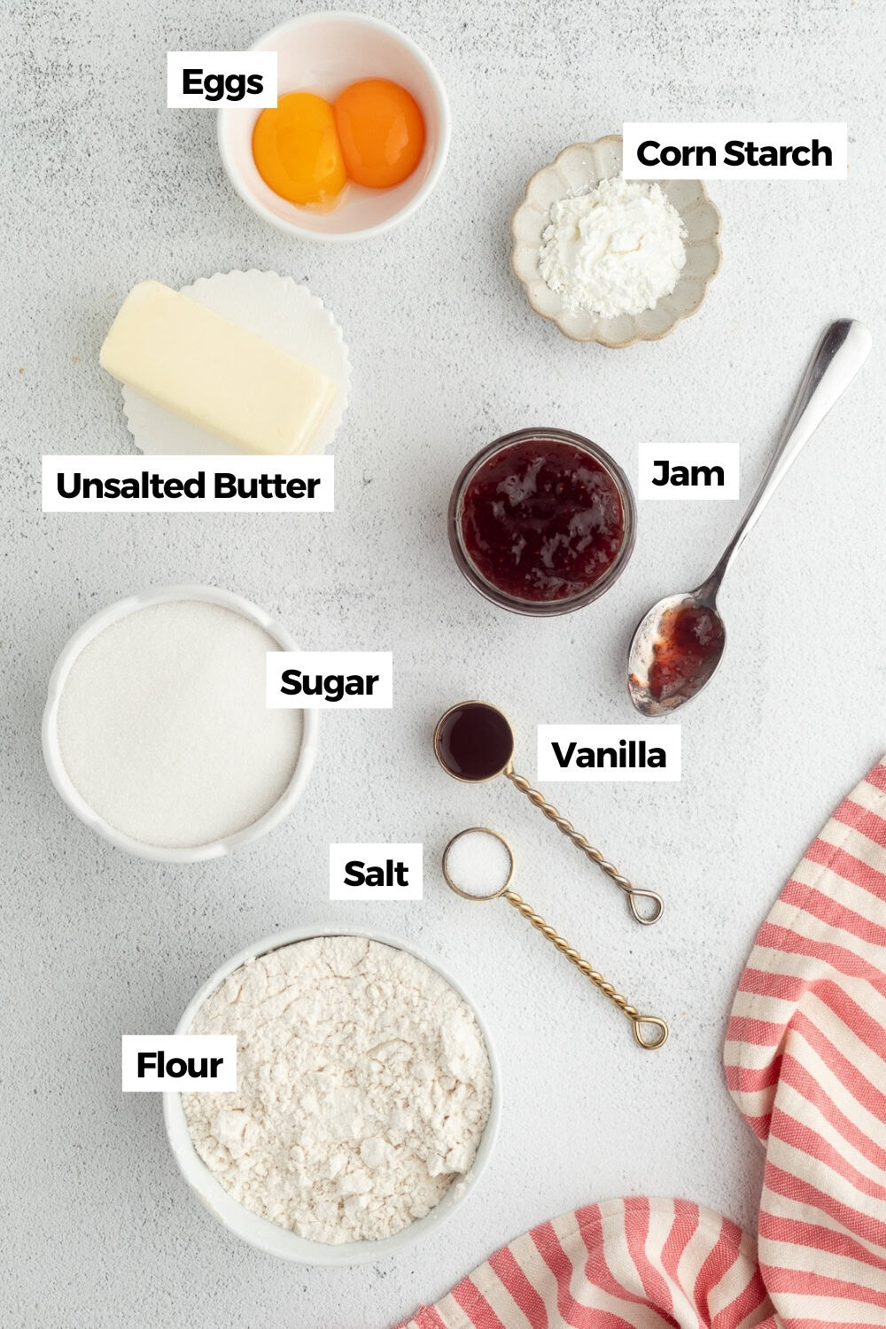 Thumbprint cookies are buttery, melt-in-your-mouth shortbread cookies rolled in sugar, filled with fruit jam, chocolate, caramel, and more. Thumbprint cookies ingredients with text labels overlaying each ingredient.