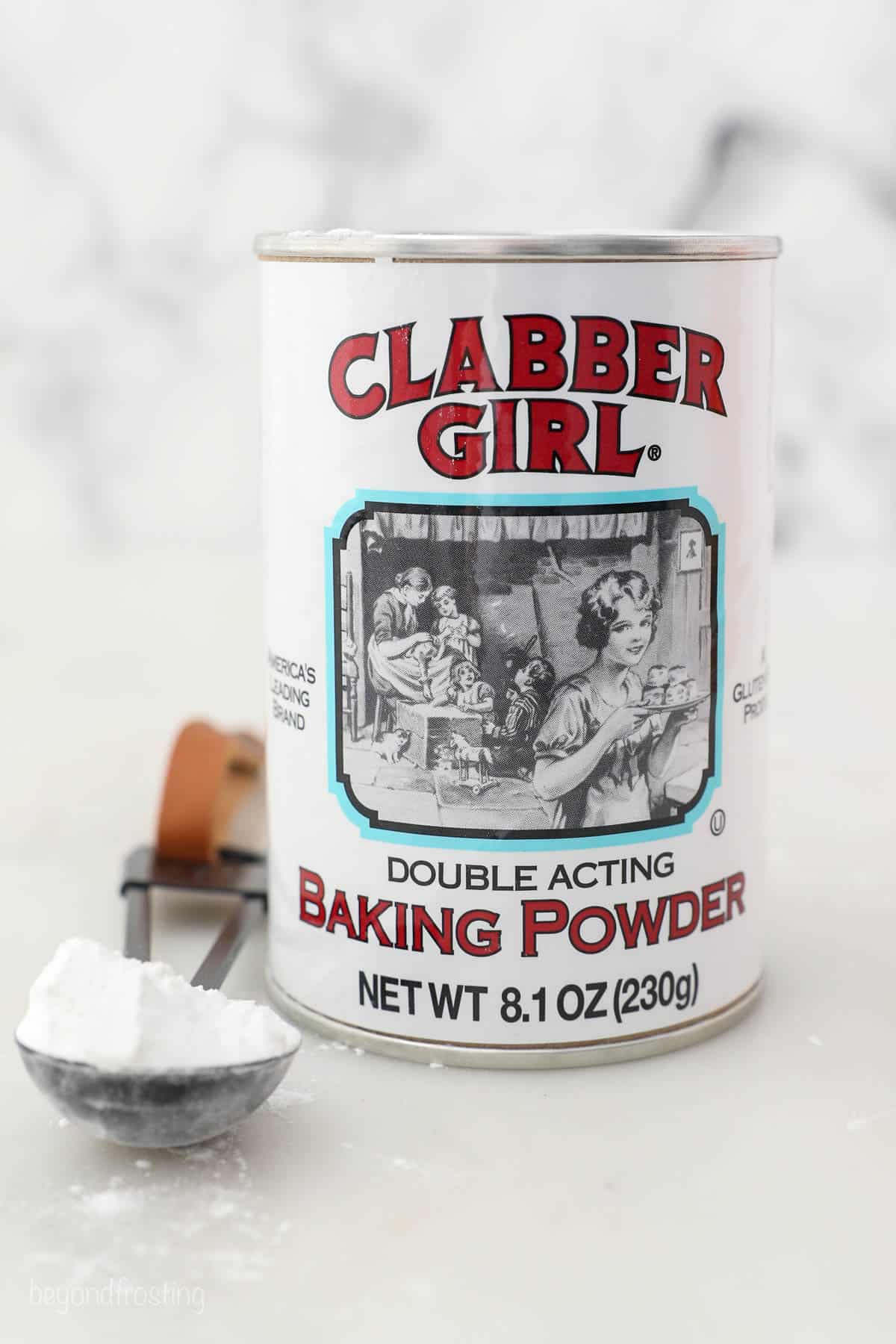 A can of double acting baking powder beside a measuring spoon holding more baking powder