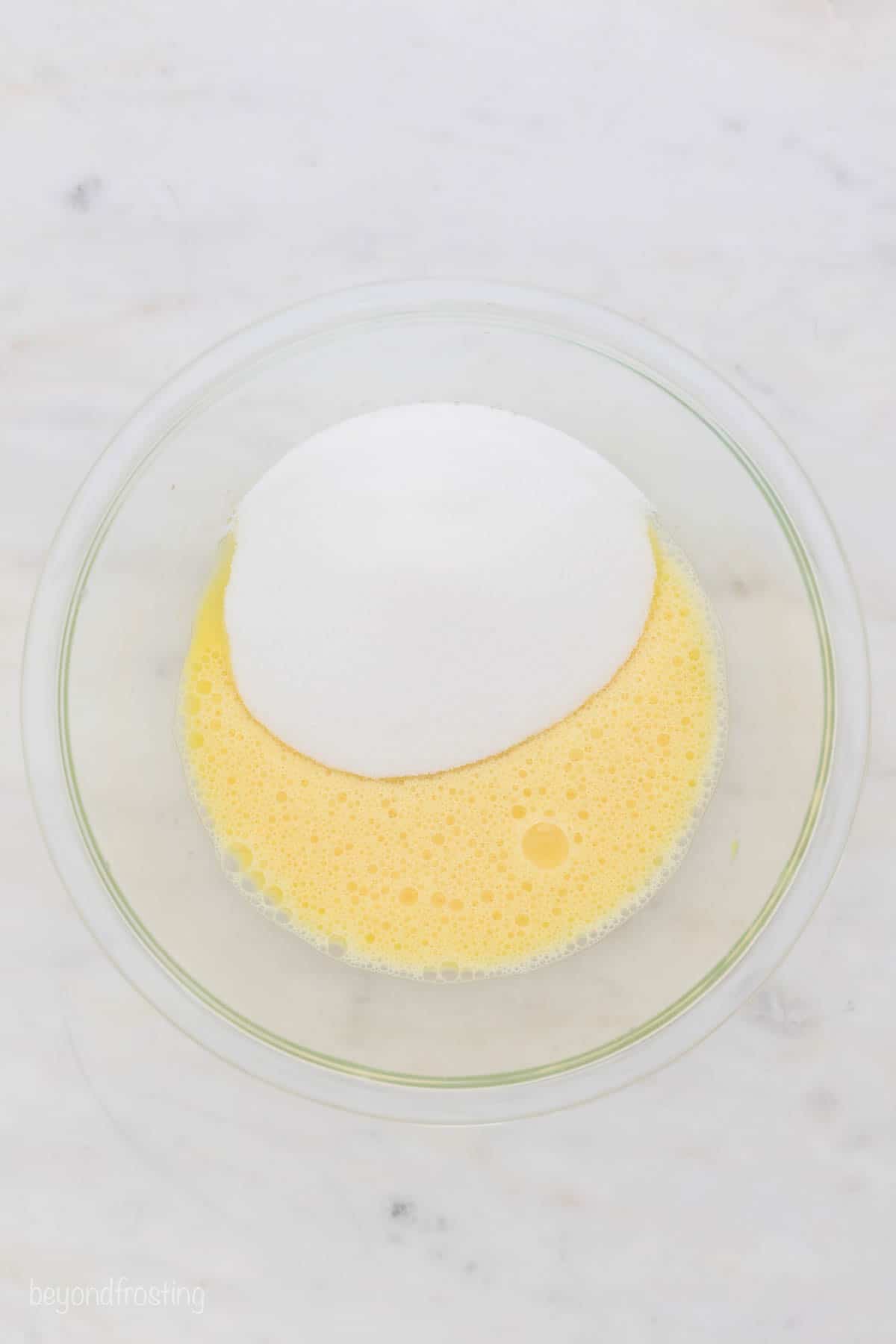 A glass bowl with whipped eggs and sugar