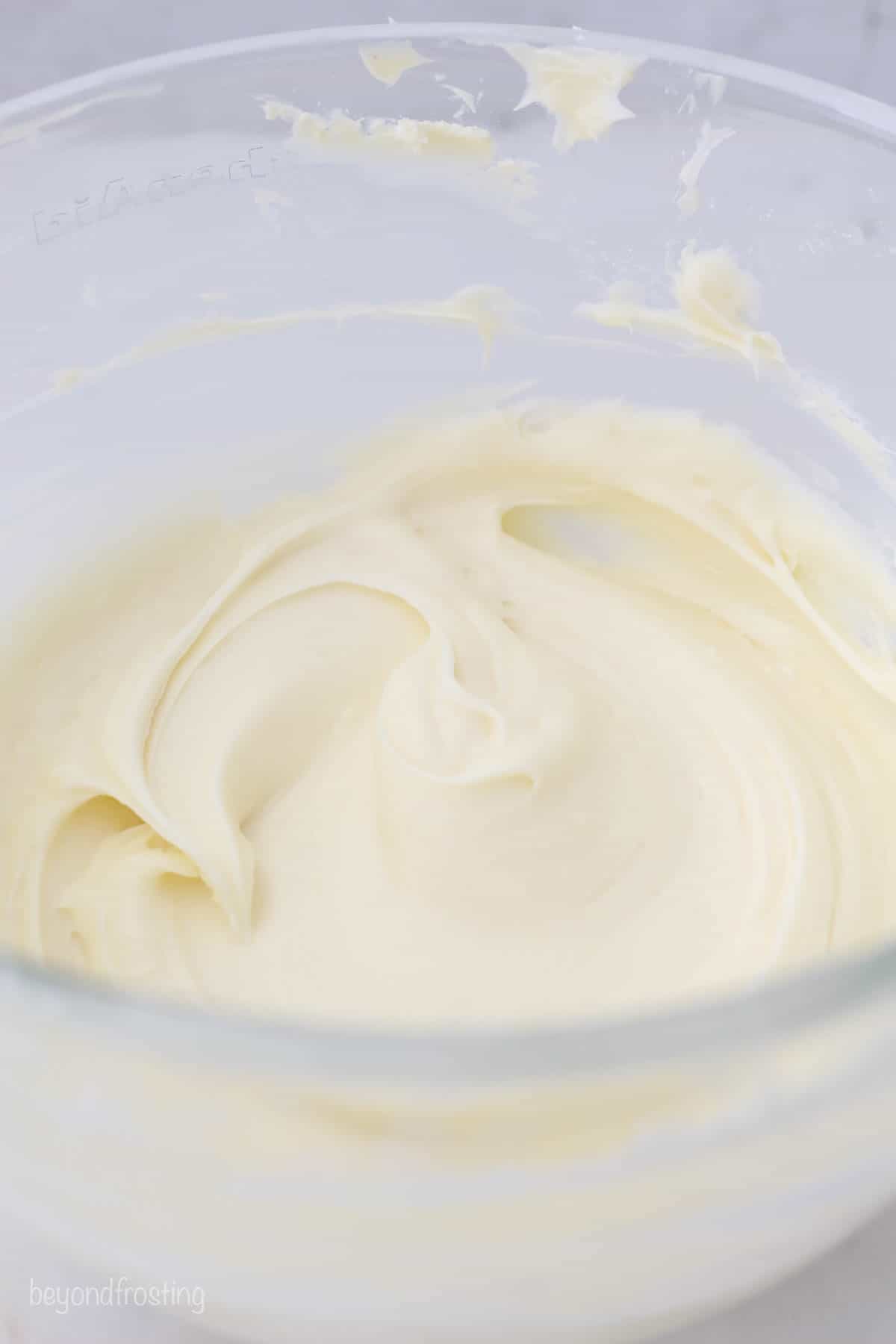 a glass mixing bowl with cream cheese frosting