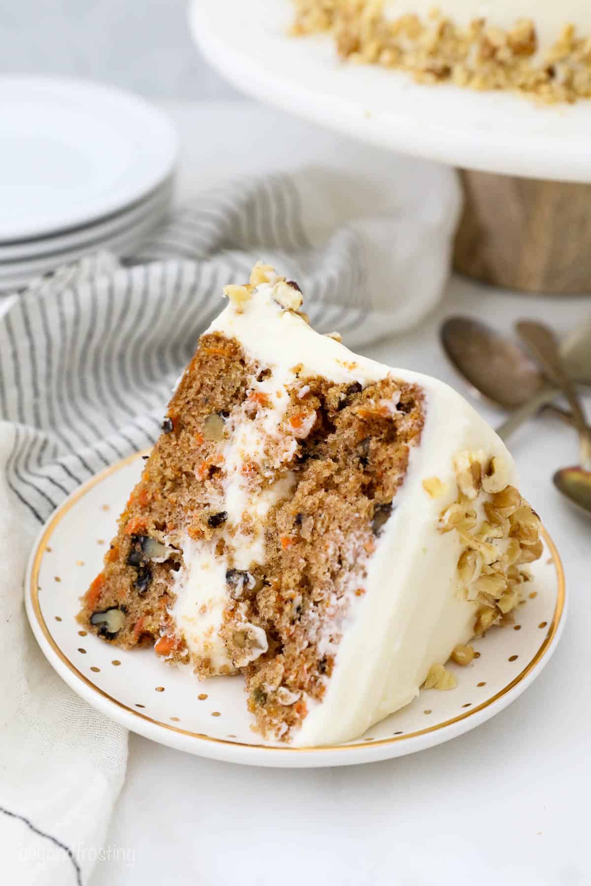 A thick slice of carrot cake on a gold polka dot plate