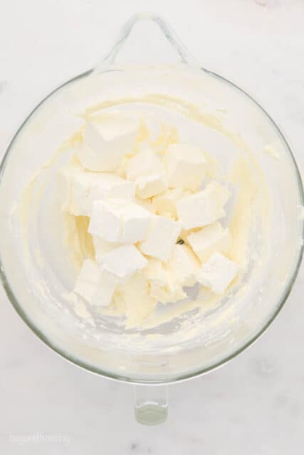 Cubed cream cheese in a glass mixing bowl