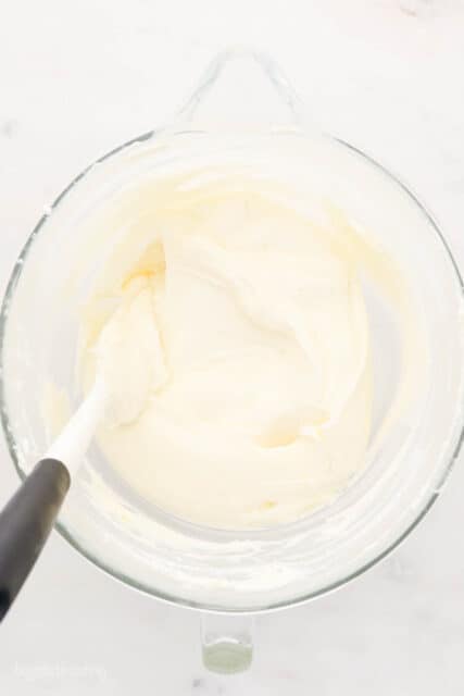 My cream cheese frosting recipe starts with cold ingredients for a thick, velvety frosting that's perfect for decorating cakes and cupcakes. A mixing bowl with cream cheese frosting and a white spatula.