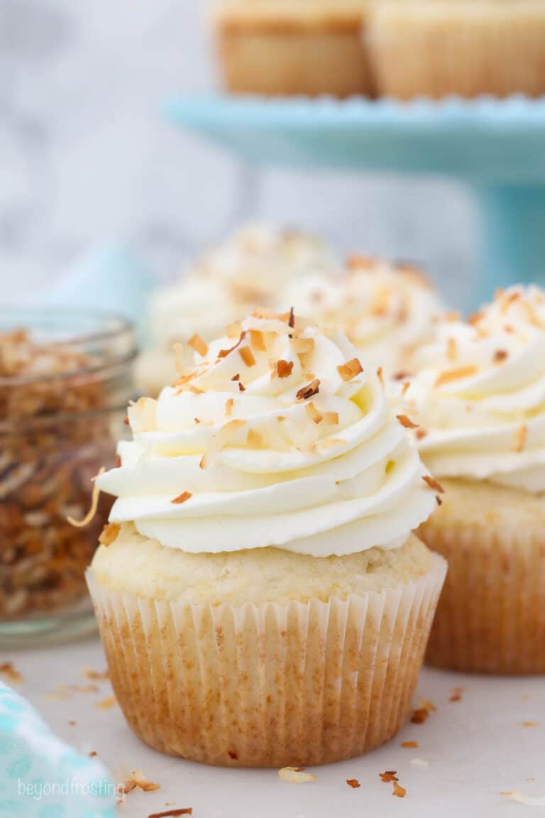 Frosted coconut cupcakes garnished with toasted coconut flakes