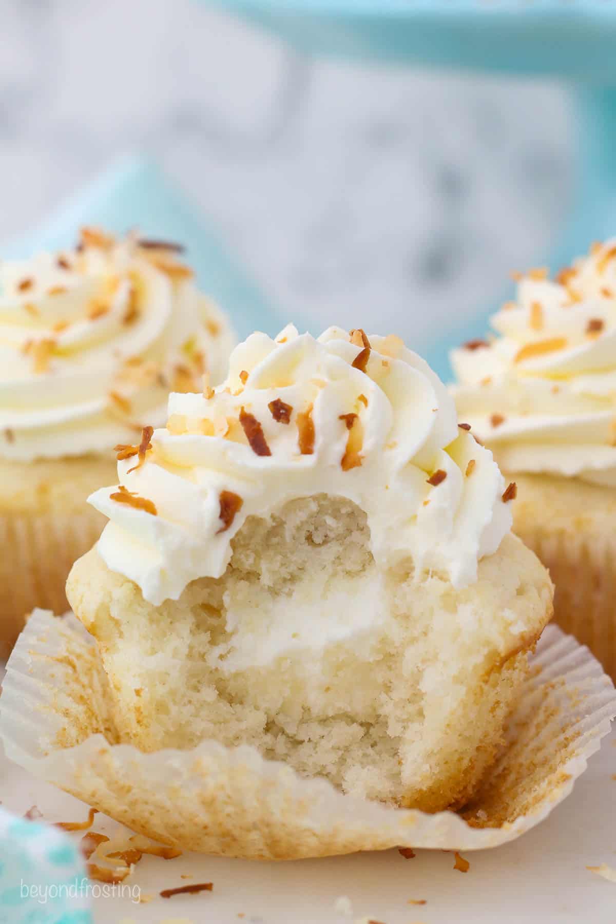 a frosted coconut cupcake with a bite taken out
